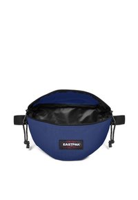 Blaue Nylontasche mit einem schwarzen Reißverschluss und innerer Fütterung. Verfügt über ein Eastpak-Logo auf der Vorderseite, ein verstellbares Kabel und eine abgerundete Form.
