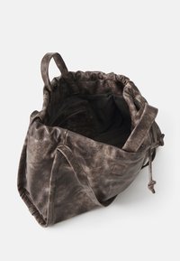 Sac à cordon en cuir marron au toucher doux, avec poches intérieures et poignées robustes. Présente une finition légèrement usée et marbrée.