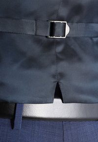Tessuto blu scuro con una superficie liscia presenta una fibbia argentata. Una cintura nera è visibile sotto, a fissare un design su misura.