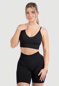Zwart geribd sportset bestaande uit een cropped beha-top met een V-hals en verstelbare bandjes, gecombineerd met een hoge taille short.