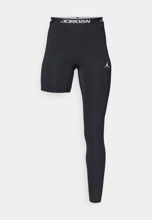 Leggings sportivi neri con design aderente, caratterizzati da una sezione ritagliata su una gamba e un logo bianco "JORDAN" sulla vita e sul lato.