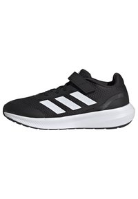 Zapatillas deportivas negras con parte superior de malla, diseño de tres rayas en blanco y una correa de velcro. Presentan una suela texturizada y punta redondeada.
