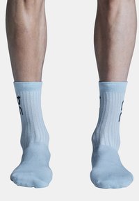 Chaussettes de cheville côtelées bleu clair avec une texture douce, présentant une inscription noire sur le devant et un design ajusté en haut.
