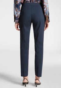 Merilsin räätälöidyt housut, joissa on sileä pinta, keski korkeudella oleva vyötärö, huomaamattomat takasaumat ja kapea malli nilkkoihin saakka.