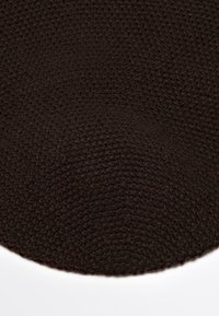 Dark brown crochet knit hat with a circular pattern and a small brown tag attached.