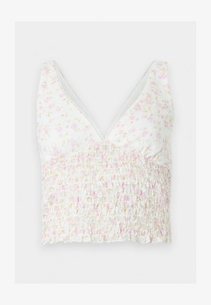 Top court blanc sans manches avec motif floral rose et beige et tissu froncé à la taille, avec un décolleté profond en V.
