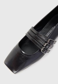 Chaussure en cuir noir à bout carré avec trois accents de bride et boucles, finition élégante et intérieur rembourré pour plus de confort.
