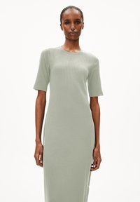 Hellgrünes, geripptes Midi-Kleid mit kurzen Ärmeln und rundem Ausschnitt, das eine lockere Passform und subtile Seitenschlitze aufweist. Glatte Textur.