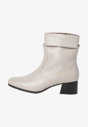 Bottine en cuir beige avec un revers souple, un bout pointu et un talon empilé. Présente des coutures discrètes et une texture lisse.