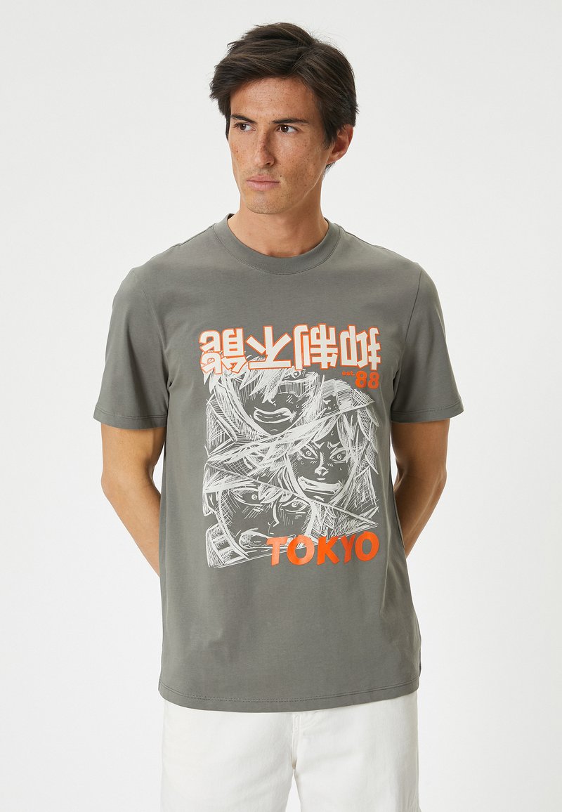 Grijze katoenen t-shirt met een grafische print van gezichten in het wit, met oranje tekst "TOKYO" en gestileerde karakters erboven.