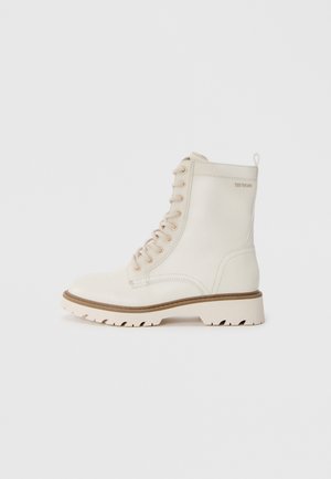 Weiße Leder-Schnürstiefel mit runder Zehenpartie, beiger Gummisohle und kleiner Zuglasche hinten. Verfügt über dezente Nähtdetails.