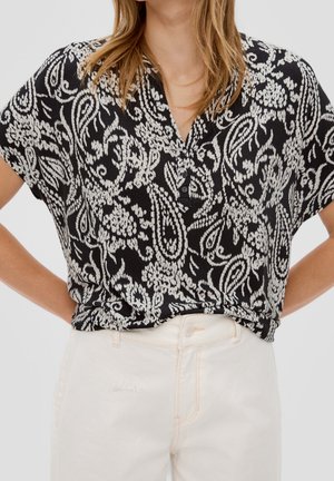 Haut à manches courtes à motif noir et blanc avec un décolleté en V et trois boutons au col. Tissu doux avec une coupe décontractée.