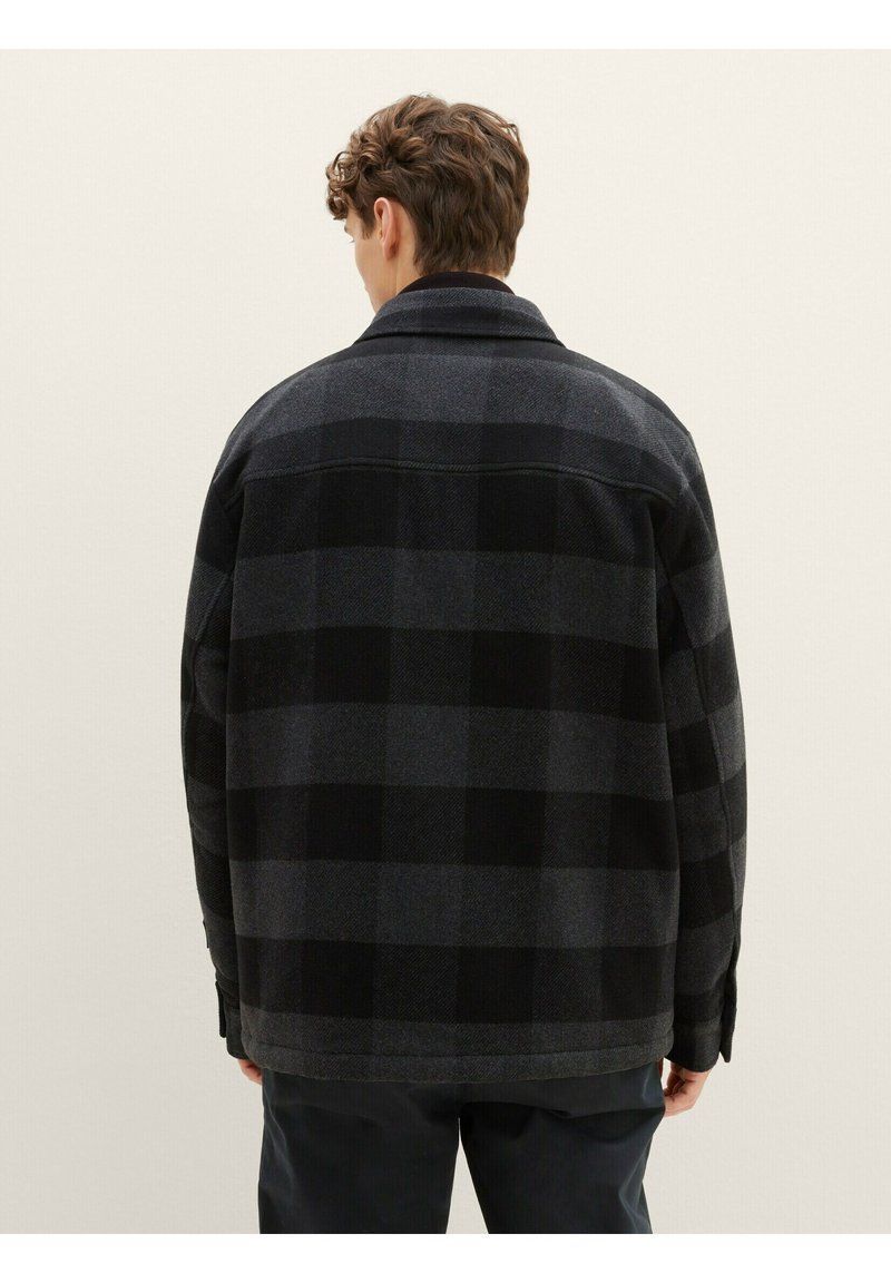 Schwarz-graue karierte Jacke, aus Wollmaterial, oversized Schnitt, Punktkragen, Rückansicht, die die gemusterte Textur und Details an den Bündchen zeigt.