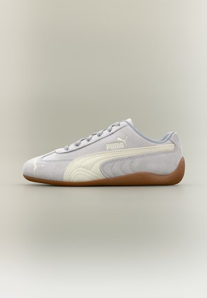 Baskets Puma en daim gris clair avec détail de bande blanche et semelle en gomme, vues de côté extérieur sur fond neutre.