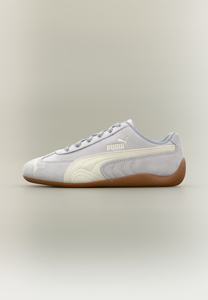Hellgrauer Puma Veloursledersneaker mit weißem Streifendetail und Gummisohle, von der Außenseite vor neutralem Hintergrund betrachtet.