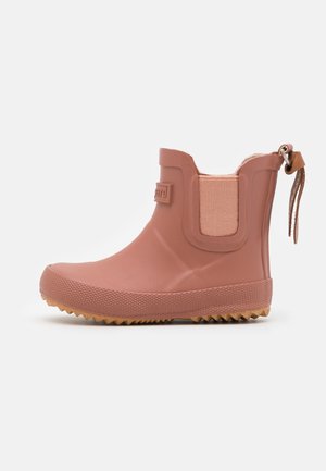 Kort pink gummistøvle til anklen med tekstureret sål, elastisk sidepanel og trækstrop med læderrem bagpå.