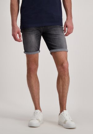 Donkergrijze denim shorts met opgerolde zoom, gecombineerd met witte sneakers. De shorts hebben een klassiek ontwerp en subtiele vervaging.