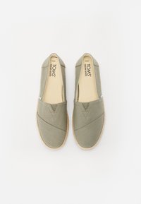 Grüne Canvas-Slipper mit strukturiertem Obermaterial, Canvas-Futter und Akzenten im Jute-Stil an der Sohle. Verfügt über ein V-förmiges Zehendesign.