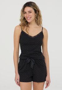 Set di pigiama nero composto da una canotta con pizzo e pois, con spalline regolabili, abbinata a pantaloni corti con vita annodata.