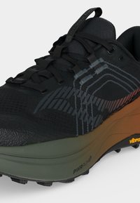 Chaussure de trail noire et grise avec une semelle intermédiaire marron, une semelle extérieure Vibram et des lacets noirs, montrant les détails latéraux et avant.