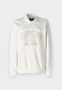 Sudadera de algodón blanca con cuello tipo polo, tres botones y texto bordado "CONVERSE Chuck Taylor ALL*STAR" en beige claro.