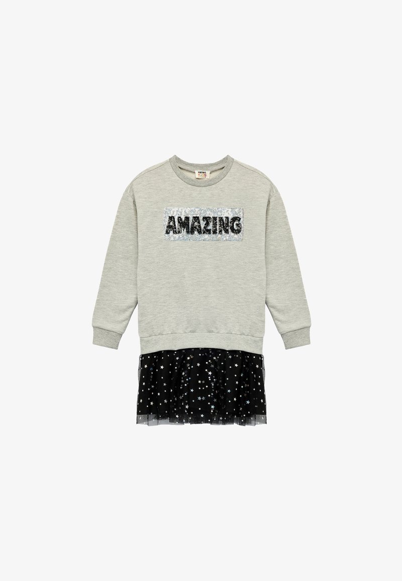 Sweat-shirt gris clair à manches longues avec le mot "AMAZING" en sequins sur le devant et une jupe en tulle noire ornée de motifs d'étoiles argentées attachée à l'ourlet.