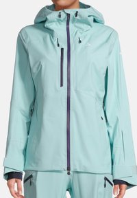 Water-resistant alpine jacket in light blue, featuring a zip front, adjustable hood, and purple accents. Includes pocket zippers and elastic cuffs.