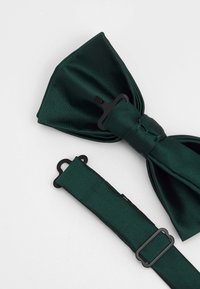 Green satin bow tie with a textured finish, featuring a black adjustable strap and a metal clip for attachment.