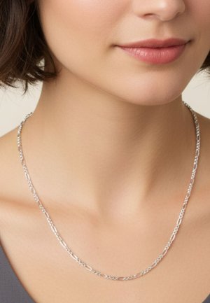 Silberkette mit verlängerten ovalen Gliedern, glatter Textur und zartem Design, die auf nackter Haut am Halsansatz liegt.