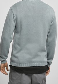 Světle modrý pletený svetr s kulatým výstřihem, texturovaná látka, žebrované manžety a lem. Nositelný přes černou košili, nabízí pohodlný střih.