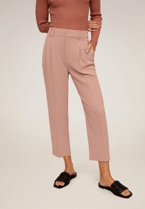 Světle růžové kalhoty na míru s vysokým pasem, záhyby a zkrácenou délkou, doplněné černými páskovými sandály. Texturovaný povrch látky.