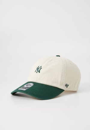 Casquette de baseball en coton couleur crème avec une visière vert foncé, présentant un logo brodé à l'avant et une étiquette sur le côté.