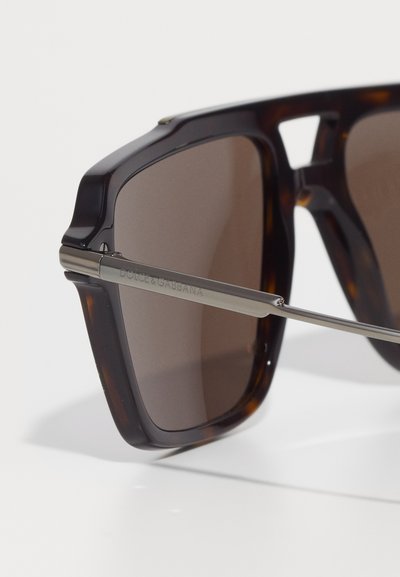 Ochelari de soare cu rame țestoasă, cu lentile întunecate, având un cadru gros și accente metalice argintii. Gravura "Dolce & Gabbana" pe braț.