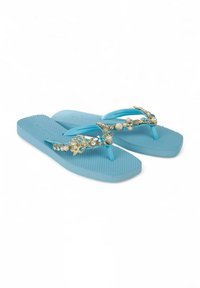 Chanclas de goma azul claro con fondo texturizado; detalles decorativos en dorado con toques de turquesa y perlas en las correas.