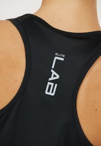 Mustan urheilullinen tank top, jossa on urheilullinen selkädesign, harjattu kangas ja heijastava valkoinen "ELITE LAB" -logo yläselässä.