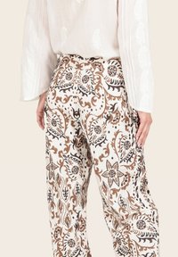 Pantaloni leggeri e a fantasia in crema con intricati motivi floreali marroni e neri. Stile a gamba larga con una vestibilità rilassata e tessuto testurizzato.