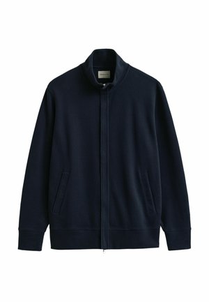 Veste bleu marine à fermeture éclair intégrale avec col montant, deux poches latérales, poignets et ourlet côtelés, présentée sur un fond blanc.