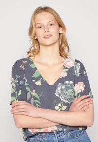 Top de manga curta em tecido cinza escuro, com um padrão floral em tons de rosa e verde. Design leve e texturizado.