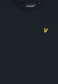Dark navy T-shirt made of cotton, featuring a round neckline and an embroidered yellow eagle logo on the left chest.