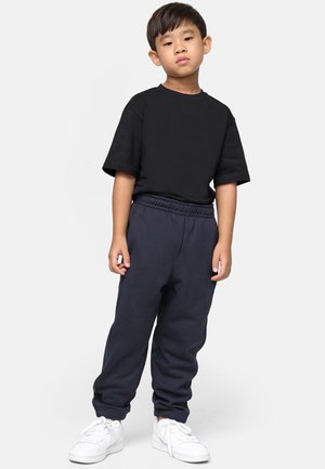 Schwarzes T-Shirt mit kurzen Ärmeln, kombiniert mit marineblauen Sweatpants mit elastischem Bund, abgerundet mit weißen Turnschuhen für einen lässigen Look.