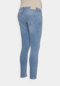 Jeans de ganga azuis com um corte justo, cintura média e dois bolsos traseiros. Um tom claro com desbotamento suave e uma etiqueta costurada na cintura.