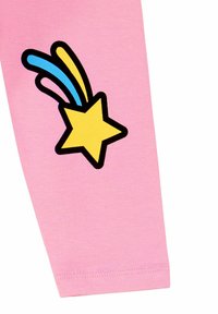 Tela de algodón rosa con un gran gráfico de estrella de contorno negro, que presenta líneas de disparo azules y amarillas. Textura suave, diseño casual.