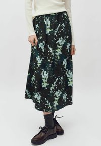 Midi sukně s květinovým vzorem v tmavě zelené, světle modré a černé barvě. Elastický pas, splývavá látka, kombinovaná s tmavými šněrovacími botami a šedými ponožkami.