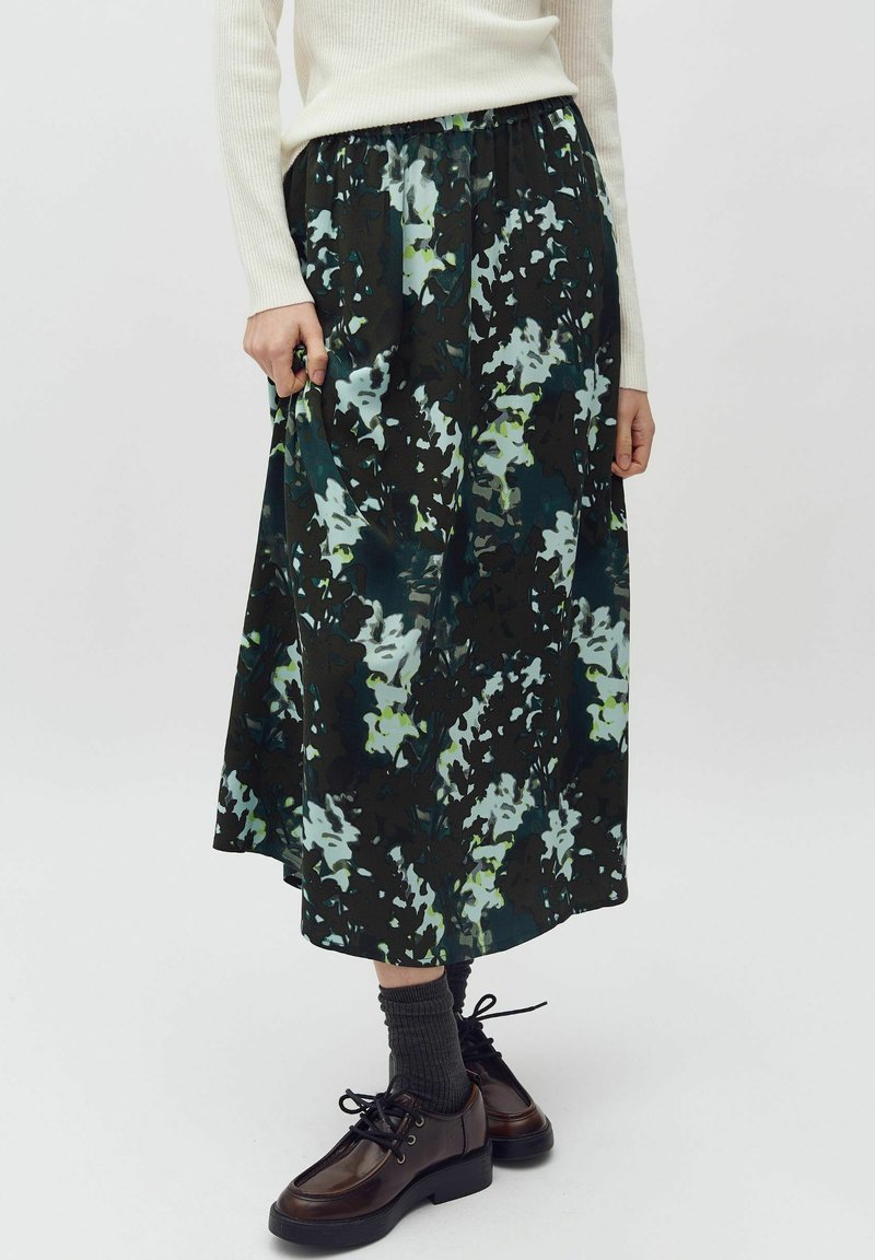 Midi sukně s květinovým vzorem v tmavě zelené, světle modré a černé barvě. Elastický pas, splývavá látka, kombinovaná s tmavými šněrovacími botami a šedými ponožkami.