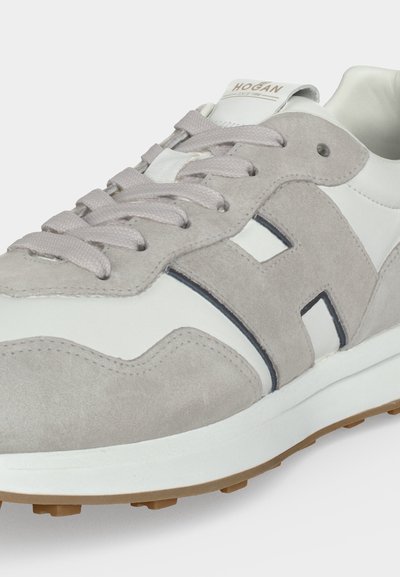 Baskets en daim blanc et gris clair avec lacets et grand motif "H" sur le côté, dotées d'une semelle blanche et d'une semelle extérieure en gomme.