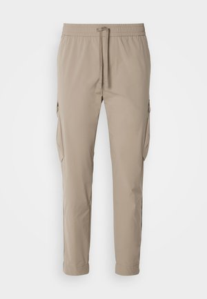 Beige cargo broek met een elastische tailleband en trekkoord. Voorzien van zijzakken en een taps toelopend ontwerp, gemaakt van lichte stof.