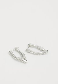 Pendientes de aro de plata con un diseño ondulado, que cuentan con una fila de pequeñas piedras de rhinestone transparentes a lo largo de un borde, acabado metálico pulido.