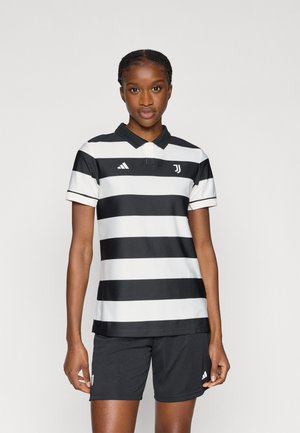 Tricou polo în dungi alb-negru cu guler, asortat cu pantaloni scurți negri. Prezintă logo-ul Adidas și emblema Juventus pe piept.