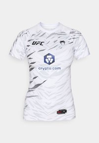 Bílé sportovní tričko s grafickými vzory, doplněné černými detaily. Na přední straně je logo UFC a modré logo crypto.com.