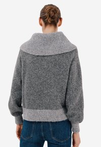 Szary sweter z wełny z dodatkiem innych włókien, z prążkowanym wysokim kołnierzem, skróconym fasonem i długimi rękawami, o miękkiej teksturze i kontrastującym jaśniejszym dolnym pasem.